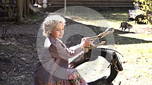 Portrait of little pretty girl dressed in traditional costume standing with trappings in rural landscape, village. a cat