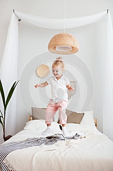 Portrait Little pretty smiling girl playing and jumping in bedroom