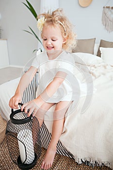 Portrait Little pretty smiling girl in white dress playing in white room