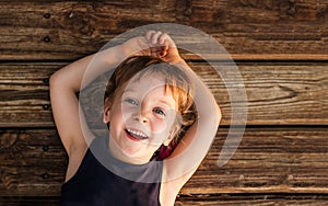 Portrait of a little red-haired girl, lying on wooden floor.