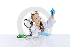 Portrait of little school girl, kid in white big gown as chemist, scientist doing experiment with multicolored chemical