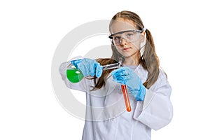 Portrait of little school girl, kid in white big gown as chemist, scientist doing experiment with multicolored chemical