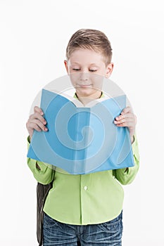 Portrait of little schoolboy with book on white background.