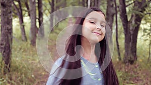 Portrait. A little shy girl walks in the park and smiles