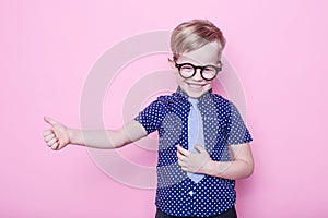 Portrait of a little smiling boy in a funny glasses and tie. School. Preschool. Fashion. Studio portrait over pink background