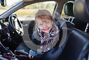 Portrait of little smiling girl in car inside