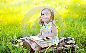 Portrait of little smiling girl child with book sitting