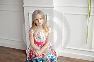 Portrait of little smiling girl child in colorful dress posing indoor