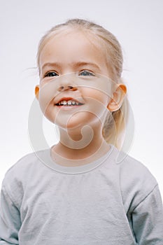 Portrait of a little smiling girl in joyful anticipation on a gray background