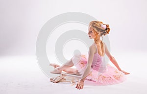 Portrait of a little tender red-haired girl in a pink tutu with pointe shoes, dreaming of becoming a ballerina