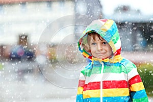Portrait of little toddler boy playing on rainy day. Happy positive child having fun with catching rain drops. Kid with