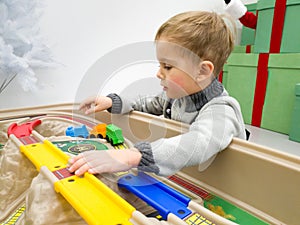 Closeup portrait of little toddler boy playing with toy trains and tracks