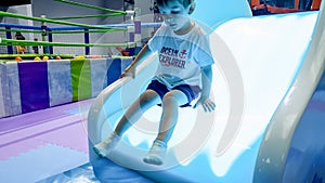 Portrait of little toddler boy riding on the colorful illuminated slide on the palyground at amusement park photo