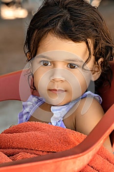 Portrait of little toddler girl sitting on chair at the beach cafe, summer vacation and childhood memories concept