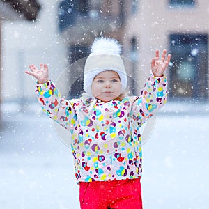 Portrait of little toddler girl walking outdoors in winter. Cute toddler eating sweet lollypop candy. Child having fun