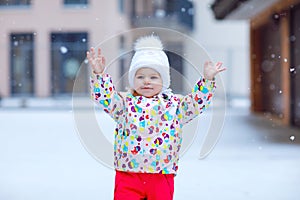 Portrait of little toddler girl walking outdoors in winter. Cute toddler eating sweet lollypop candy. Child having fun