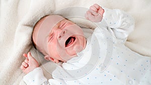 Portrait of little 2 weeks old baby boy crying in baby crib or bed