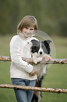 Portrait of a little young girl who stands and hugging the dog. Lifestyle