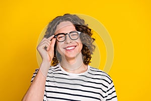 Portrait of logic thinking young handsome teen guy touch eyeglasses cheerful enjoy new spectacles isolated on yellow