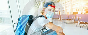 Portrait of lonely teen solo traveler with a backpack in empty airport passenger transfer hall in protective face mask and sadly