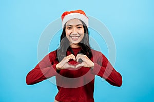 portrait, Long-haired asian girl red long-sleeved top wearing christmas hats, bring both hands her cheeks, making heart shapes on