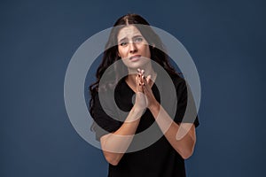 Portrait of a long-haired brunette woman in black t-shirt posing on a gray background and showing different emotions.