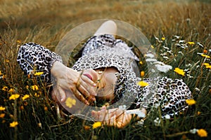 Portrait of look well smiling middle aged woman lying in wild flowers field outdoors.