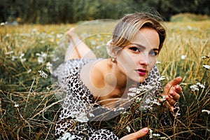 Portrait of look well smiling middle aged woman lying in wild flowers field outdoors.