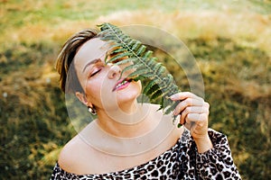 Portrait of look well smiling middle aged woman lying in wild flowers field outdoors.