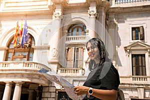 Portrait of a lost tourist holding map and searching for locations on a spanish city. Historic building on the background
