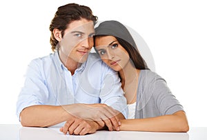 Portrait, love and couple together in a studio with white background and hand holding. Sitting, studio and smile of a