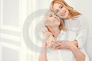 Portrait of loveful mature daughter embracing her elderly mom