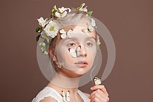 Portrait of lovely blonde woman with perfect updo hairstyle, white spring flowers and butterfly on brown background