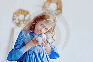 Portrait of lovely, cheerful blond girl , holding colored eggs, celebrating Easter with family