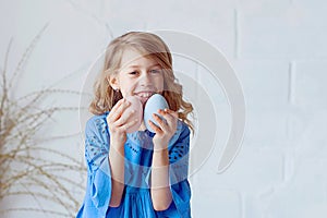 Portrait of lovely, cheerful blond girl , holding colored eggs, celebrating Easter with family