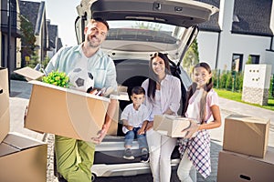 Portrait of lovely cheery family new apartment owners brother sister taking belongings from car rent leasing loan in