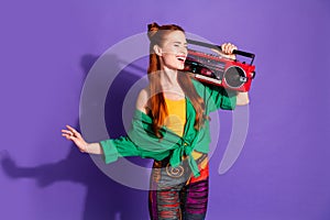 Portrait of lovely cool woman with ginger hairstyle dressed green shirt hold boombox sing song isolated on purple color