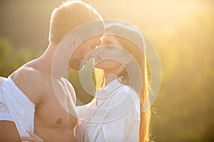 Portrait of lovely couple in love at sunset. Young sensual girlfriend glad to passionate kiss from her boyfriend