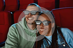 Portrait of lovely couple wearing 3d glasses smiling while watching a comedy together in cinema auditorium