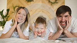 Portrait of a lovely family posing and smiling on bed in their bedroom