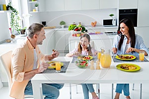 Portrait of lovely friendly family sit kitchen table enjoy tasty homemade food communicate joking morning apartment