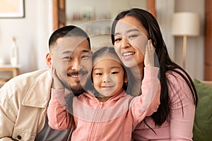Portrait Of Lovely Korean Family Of Three Embracing At Home