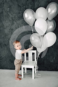 Portrait of lovely little boy happy smiling celebrating 1 year birthday. One year old european boy sitting on floor