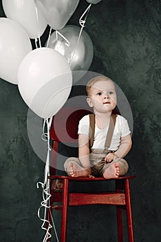 Portrait of lovely little boy happy smiling celebrating 1 year birthday. One year old european boy sitting on floor