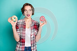 Portrait of lovely minded girl hold two donuts think yummy flavor lick lips addicted sweet lover healthy nutrition