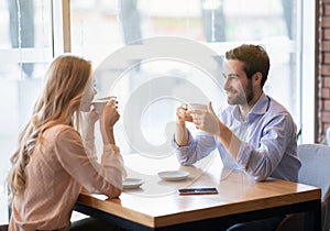 Portrait of lovely romantic couple sitting in urban cafe with fresh coffee, enjoying their date, having friendly chat