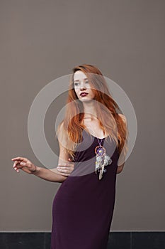 Portrait of lovely slim redhead girl in wine dress and dreamcatcher craft talisman