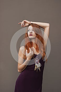 Portrait of lovely slim redhead girl in wine dress and dreamcatcher craft talisman