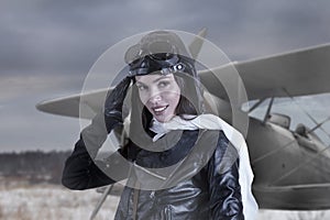 Portrait of lovely young adult woman in retro pilot costume giving military salute