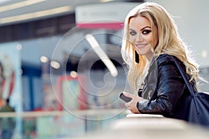 Portrait of a lovely young blonde with the eye makeup. Smiling woman with mobile phone